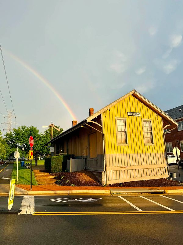 Yellow building under a rainbow with stop signs and road markings.