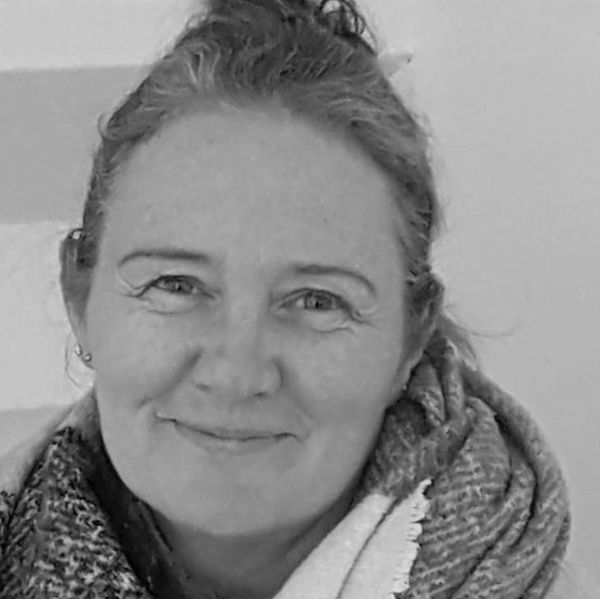 Black and white close-up portrait of a smiling woman wrapped in a scarf.