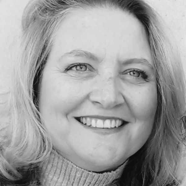 Black and white close-up of a smiling woman with light hair.