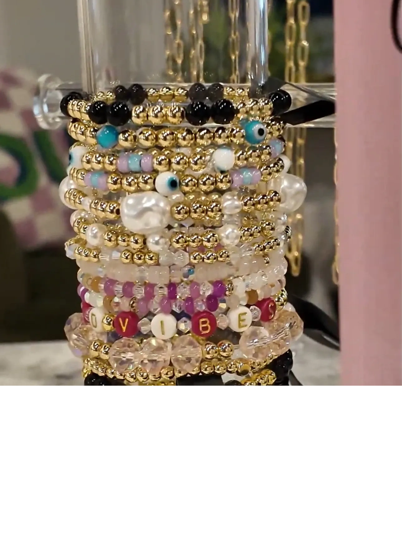 Stack of colorful beaded bracelets with gold accents and 'VIBES' spelled out on one bracelet.
