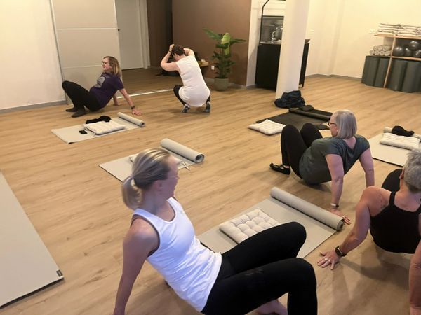 A group of women exercising on mats in a bright, spacious room.