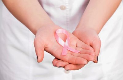 Hands of a person holding a pink ribbon