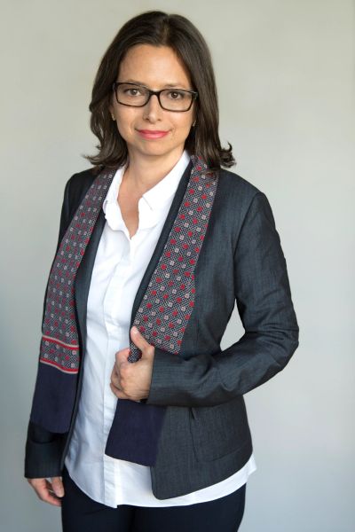 Professional woman in glasses wearing a blazer and patterned scarf.