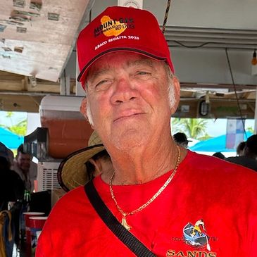 Head and shoulders picture of a man with light complexion and white hair, with a red regatta cap.