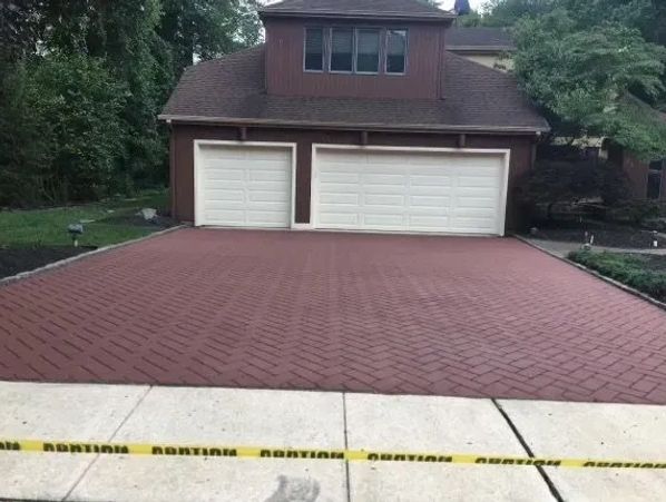 Freshly paved driveway with caution tape in front of a two-car garage.