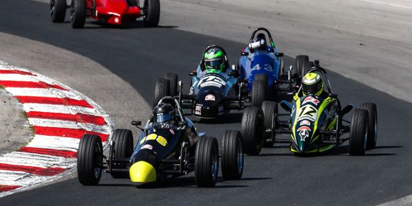 Four Formula Ford race cars competing on a curvy racetrack.