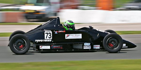 Black Formula race car number 73 speeding on track.
