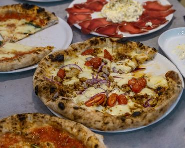 Wood-fired pizzas with various toppings and a plate of cured meat and cheese.