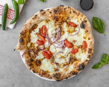 Wood-fired pizza with melted cheese, cherry tomatoes, and red onions.