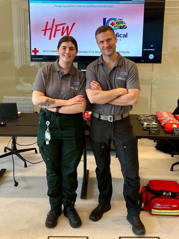 Jazz & Bruce in JC Medical Services uniform standing confidently together in a training room.