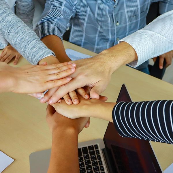 Team members stacking hands in a show of unity and collaboration.