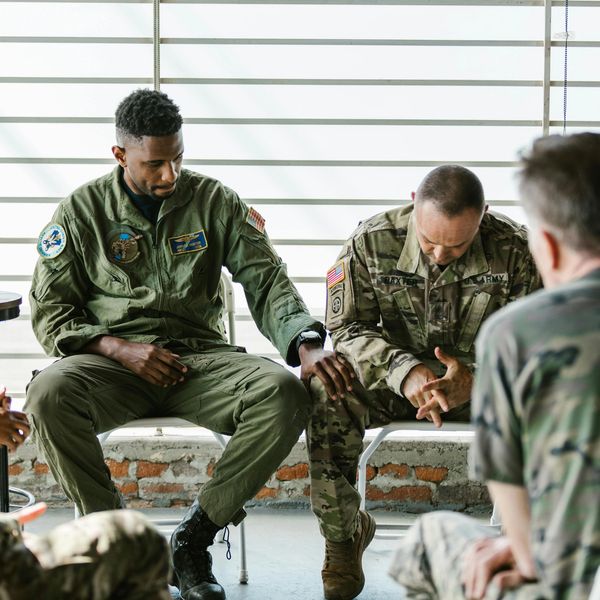 Two military personnel share a moment of support and reflection during a group meeting.