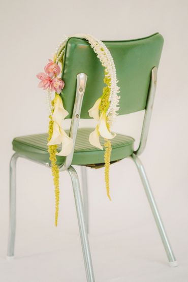 A green chair adorned with a delicate floral and pearl garland.