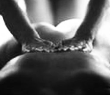 Placing of hands on the sacrum, during of a male tantric prostate massage.
