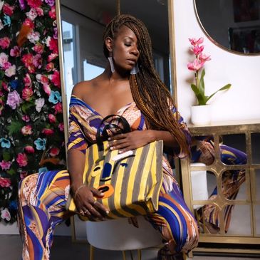 Woman with braided hair holding a colorful striped bag.