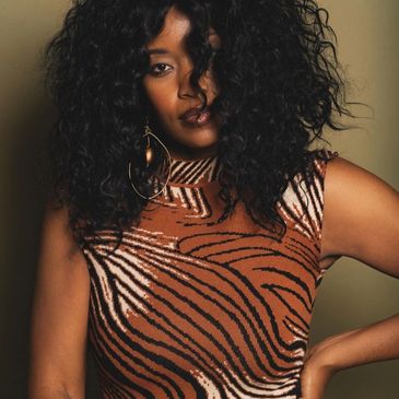 Woman with curly hair in a zebra-striped top.