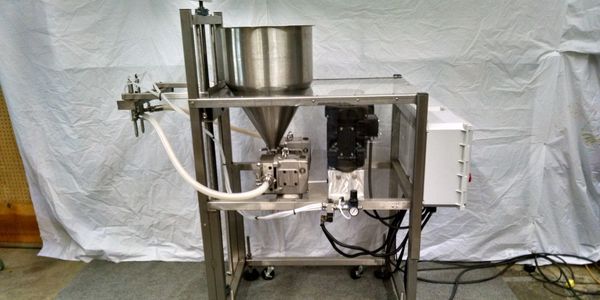 Sanitary 2 head pump filling machine set up to fill sauce into bottles.  The machine is adjustable a