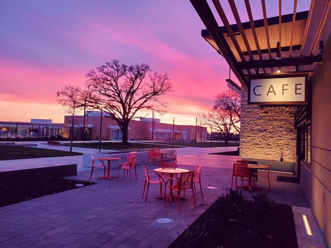 Outdoor cafe seating at sunset with vibrant pink and purple sky.