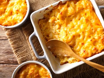 Baked macaroni and cheese in a white casserole dish with wooden spoon.