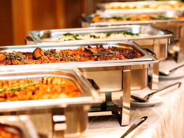 A buffet line with various hot dishes in stainless steel chafing dishes.