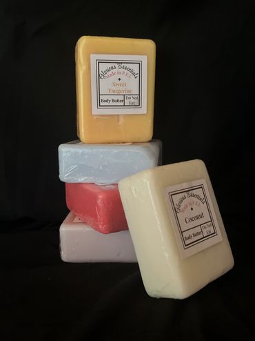 Stack of colorful Glorious Essentials body butter bars against black background.