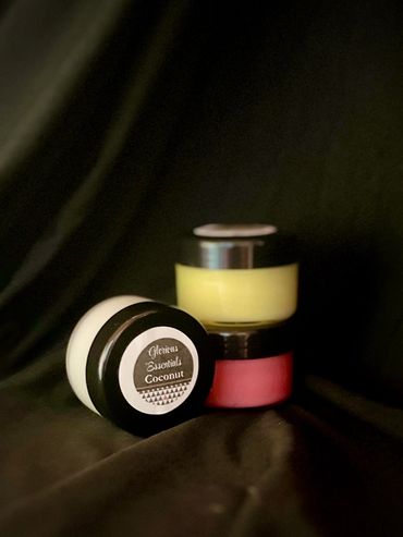 Three small containers of skincare products on a dark fabric background.