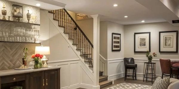 Cozy basement living area with stairs, seating, and decorative accents.