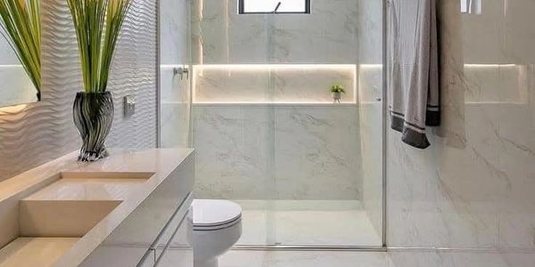 Modern bathroom with marble walls, glass shower, and sleek vanity.