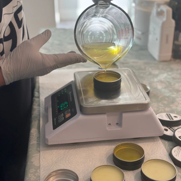 Pouring yellow liquid into small containers on a scale.