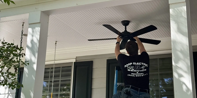 Electrician installing a ceiling fan on a covered porch—ceiling fan installation and additions.