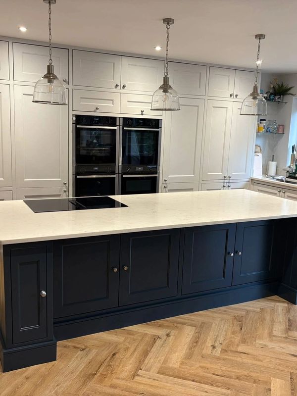 Modern kitchen with navy island and white cabinets under pendant lights.