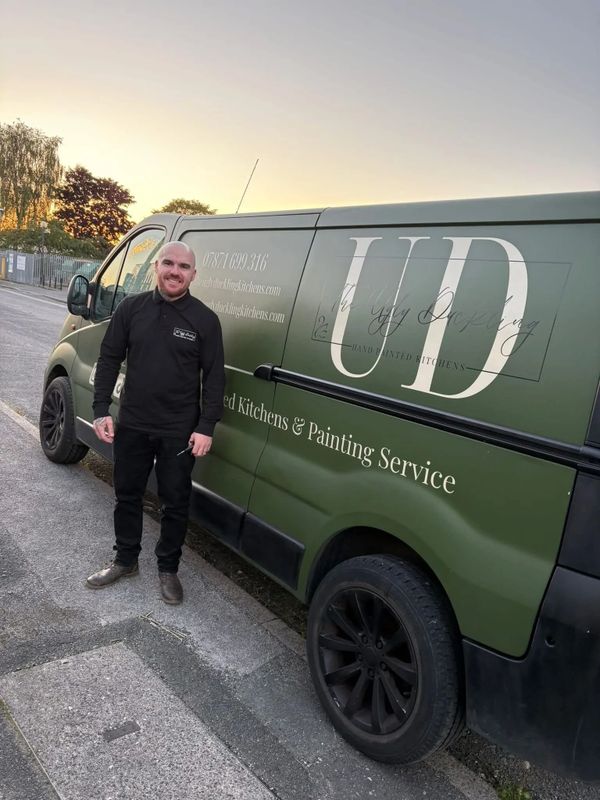 Man standing next to a green van advertising kitchen and painting services.