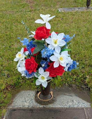 Red, white, and blue flower arrangement on a grave marker.