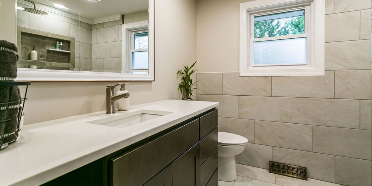 Modern bathroom remodel in Fulton, NY, by Rexyco LLC, with tiled walls and dark vanity.