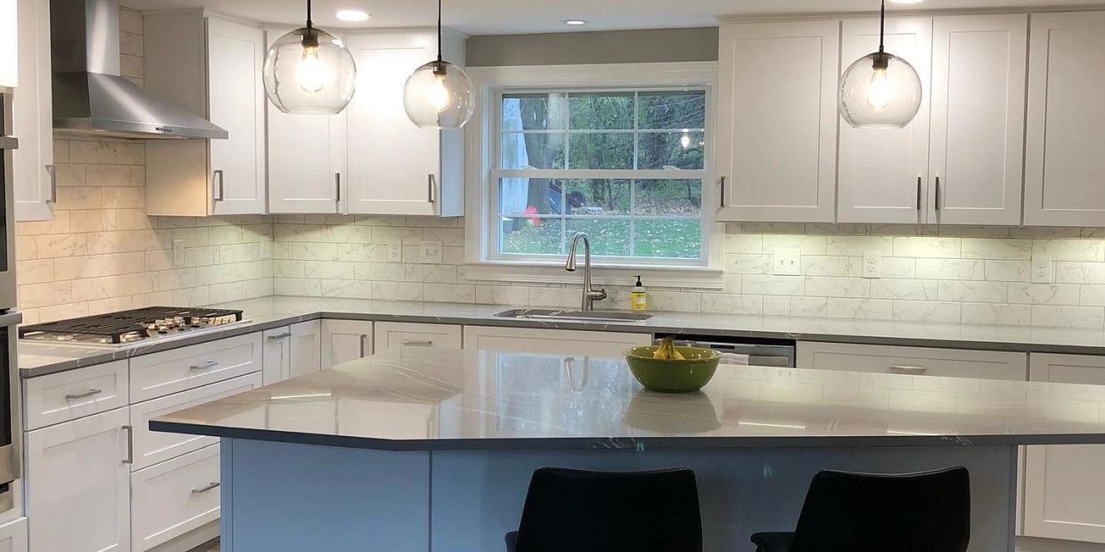 A Baldwinsville, NY, kitchen remodel by Rexyco LLC, with white cabinets, stone tops, globe lights.