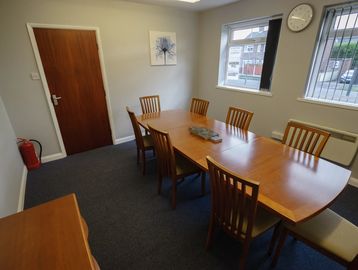 Small conference room with wooden table and chairs.