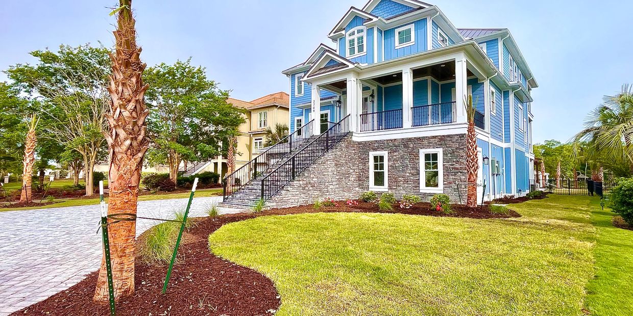 Blue two-story house with stone foundation and a landscaped lawn.