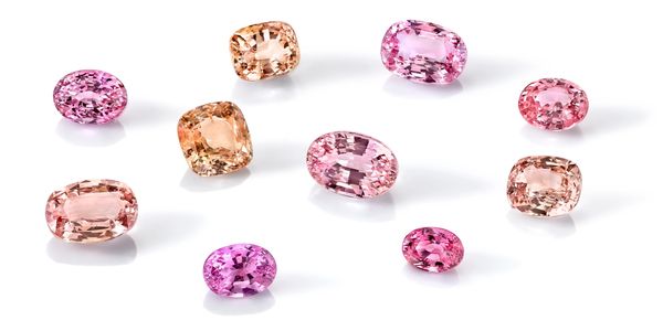 A collection of ten loose, rare Padparadscha Sapphire gemstones in a range of orange and pink hues.
