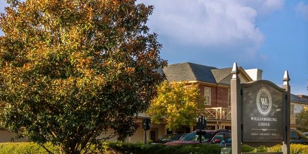 Williamsburg Lodge entrance with autumn foliage and clear sky.