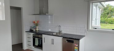 Modern kitchen with white cabinetry, black countertop, and stainless steel appliances.
