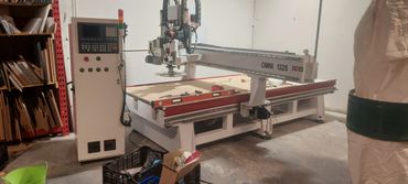 A CNC machine in a workshop surrounded by tools and materials.