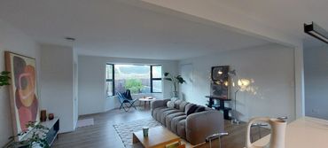 Modern living room with cozy sofa, butterfly chair, and abstract art.