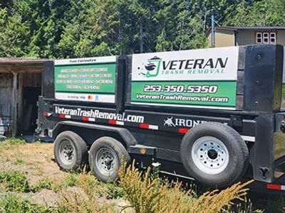 A black trailer for Veteran Trash Removal with contact info and website on the side.