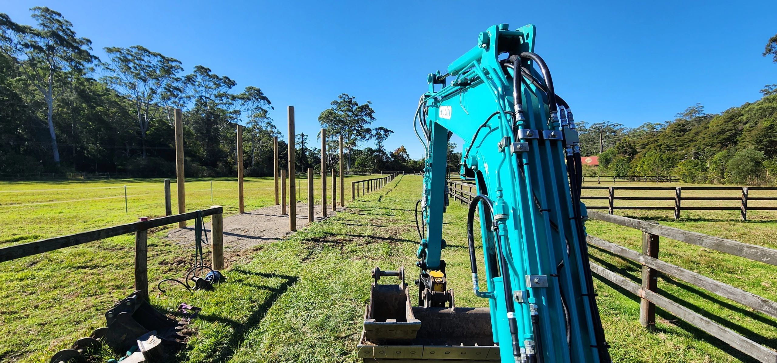 Excavator installing post in a horse paddock at ourimbah