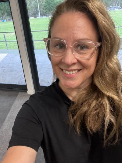 Smiling woman with glasses taking a selfie indoors.