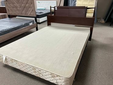 A simple wooden bed frame with a mattress in a furniture store.