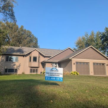 Suburban house with a roofing service sign on the lawn under clear blue sky.