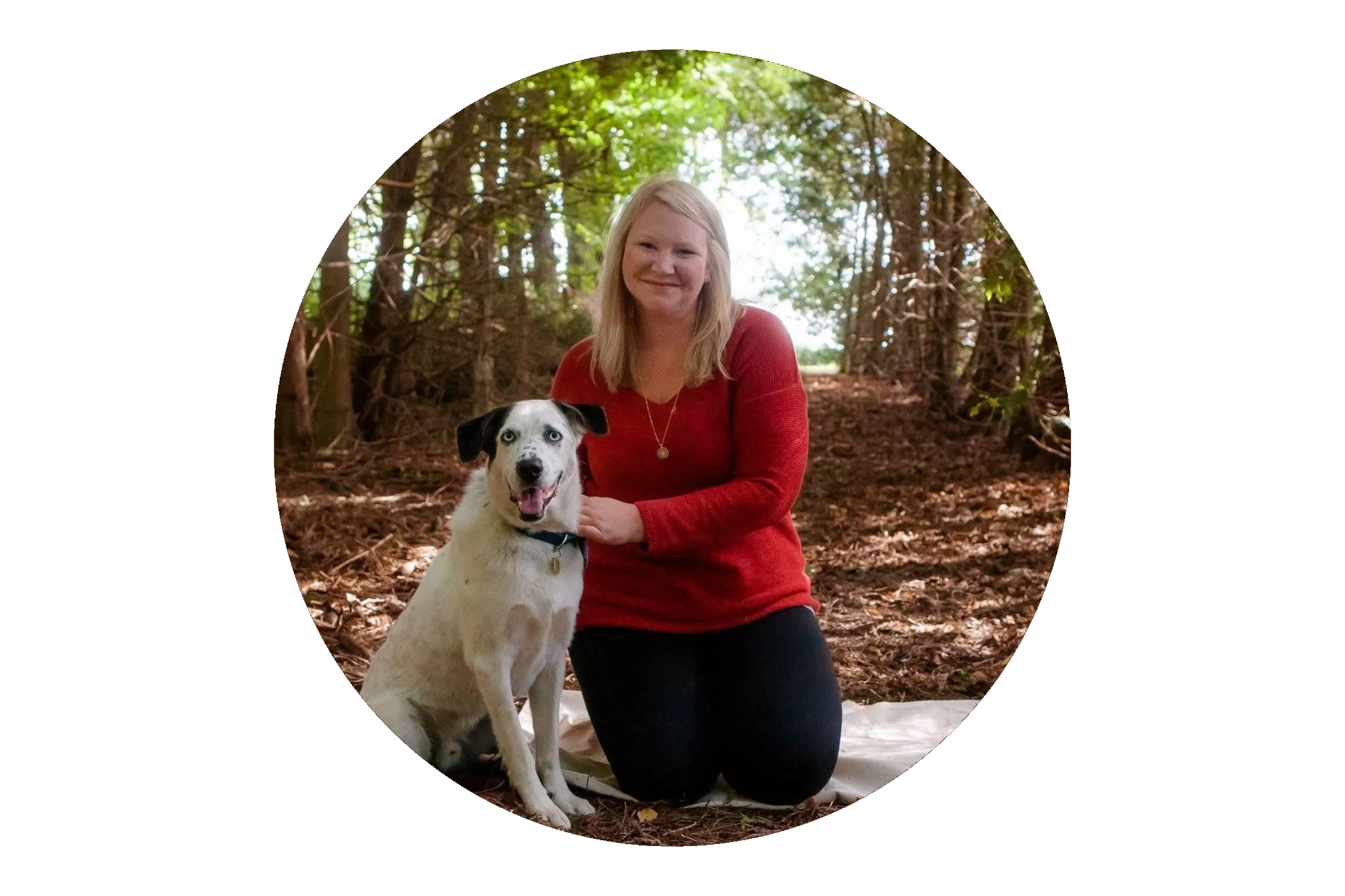 Stacey Van Riel kneeling beside her dog Domino in a wooded area.