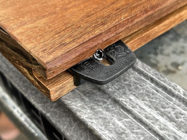 Close-up of wooden boards joined by a black plastic connector with a screw.