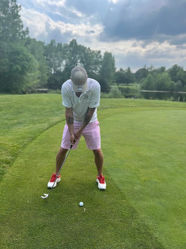 Man in pink shorts preparing to putt on a golf course.